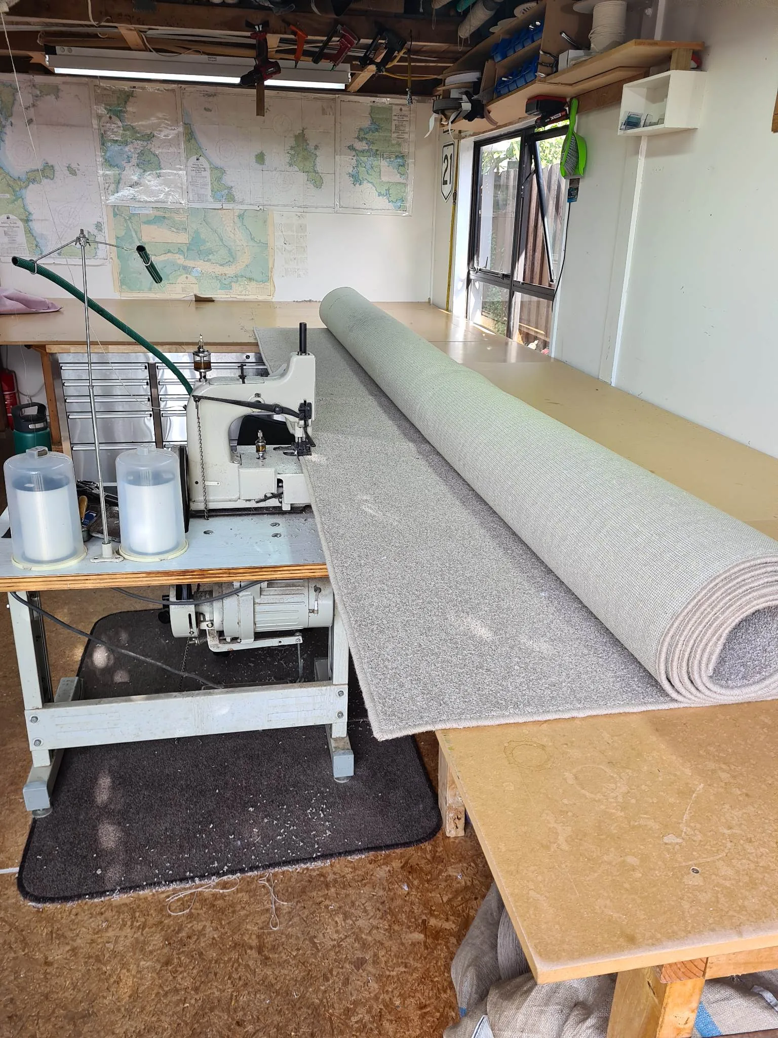 Industrial carpet overlocking machine processing grey carpet in Auckland workshop